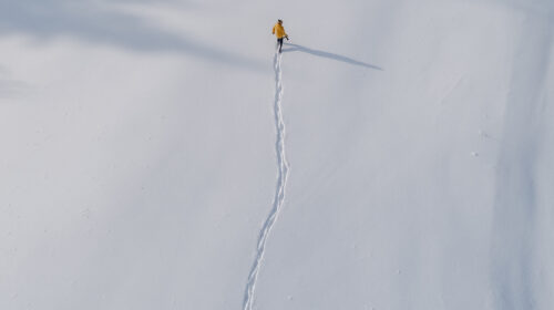 Un homme marche seul dans la neige. Derrière lui, ses traces de pas.